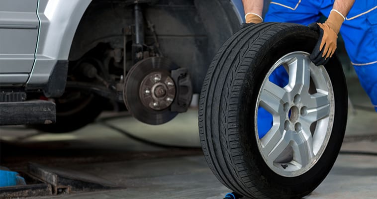 Automechanikas keičia automobilio padangą